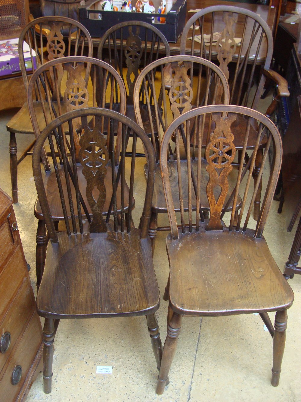 A matched set of seven beech wheelback chairs with solid elm seats, including an armchair.