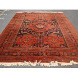 A large red ground Afghan carpet.