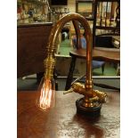 A lamp made from a brass mixer tap on a bygone weight, the on/off switch is the hot tap,