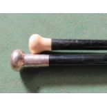 Two ebony walking canes one with ivory knop the other with engraved silver knop,