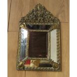 A Victorian embossed brass cushion mirror with floral and scrolling detail,