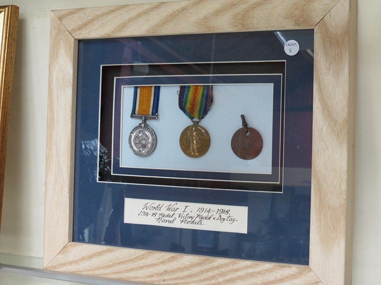 A framed display of a WWI medal pair and dog tag to S.