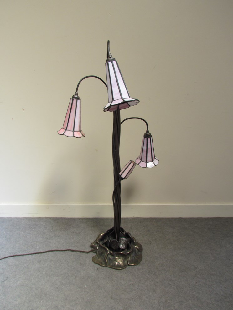 A Tiffany style lily lamp with four tall stems with trumpet form shades, ornate leaf form base,