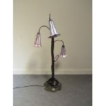 A Tiffany style lily lamp with four tall stems with trumpet form shades, ornate leaf form base,