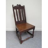 An early 18th Century oak hall chair with carved crest,