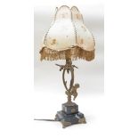 An ornate gilt table lamp of putti under branches on stepped marble base and four claw feet.