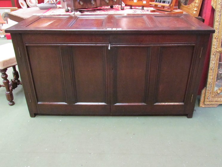 An 18th Century panelled oak coffer the hinged lid over two doors on stile feet,