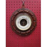 An early to mid 20th Century circular carved oak barometer,
