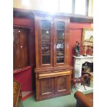 A mahogany bookcase cupboard the twin glazed doors with shelved interior over a cushion drawer and