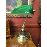 A brass bankers lamp with green glass shade