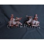 A pair of Oriental hardwood carved figures of oxen with mounted figures,