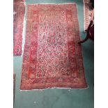 A 20th Century care worn handwoven Persian rug with central field decorated with stylized flowers,