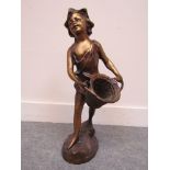 A bronze figure of a boy with basket,