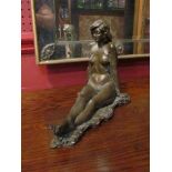 A cold cast resin bronze figure of a seated nude,