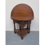 An Arts & Crafts style oak bow front side table the hinged top over canon barrel turned legs joined