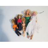A collection of Barbie style dolls and outfits,