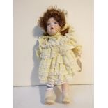 An Elsie Bailey bisque head doll in yellow outfit