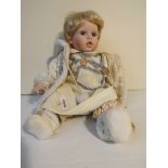 A porcelain baby doll, dressed,