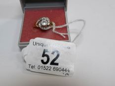 An unmarked gold ring set central stone and smaller shoulder stones,