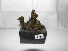 A bronze camel rider on marble plinth