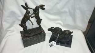 2 bronze statues of hares on marble bases, boxing/running, both signed Nike