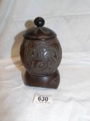 A carved coconut lidded pot on stand
