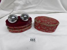 A pair of Chinese chiming 'worry' balls in fabric covered box