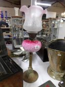 A  Victorian oil lamp with art nouveau pink glass font, brass column,