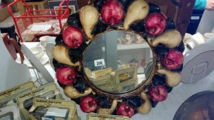 A circular mirror in fruit decorated frame