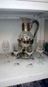A glass carafe on plated stand and 6 glasses