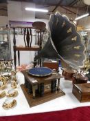 A gramaphone in wood and glass case with brass horn decorated with cherubs