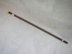 A walking cane with ivory handle shaped as a clenched fist holding a scroll