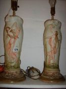 A pair of ceramic lamp bases in the style of Royal Dux decorated with semi nude figures,
