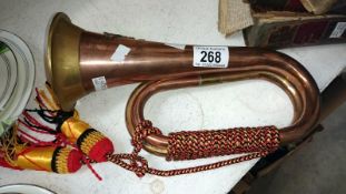 A copper and brass bugle with military badge