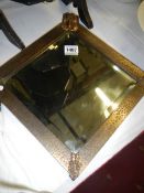 An art deco wall mirror with bronzed surround and rams head motife