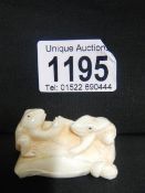 An ivory netsuke of 2 frogs on a seed