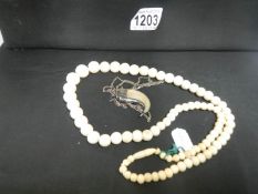 An ivory necklace and a tiger tooth with silver mount