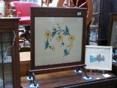 An Edwardian mahogany inlaid fire screen with silk embroidered floral panel under glass