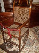 A Victorian wheel chair with cane seat and back