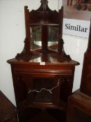 A mahogany corner cabinet with mirror back and central door