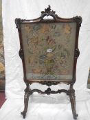 A Victorian fire screen with embroidered floral panel under glass