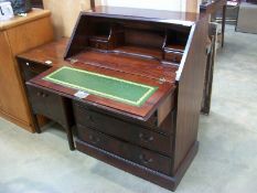 A polished mahogany effect bureau with green leather inset