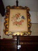 An early Victorian ebonised and laquered pole screen with embroidered panel