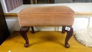 An upholstered footstool with Queen Anne legs