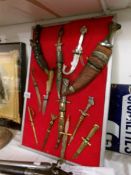 A collection of old knives and letter openers on display board