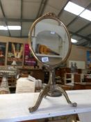 A metal framed mirror on tripod base