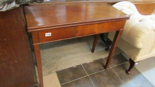 A mahogany fold over table on tapered legs