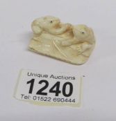 An ivory netsuke being 2 frogs on a seed