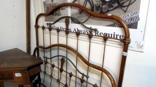 A Victorian iron bedstead with brass rail and complete with side tails