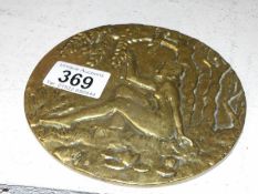 A cast brass plaque of a naked lady amongst laburnum trees